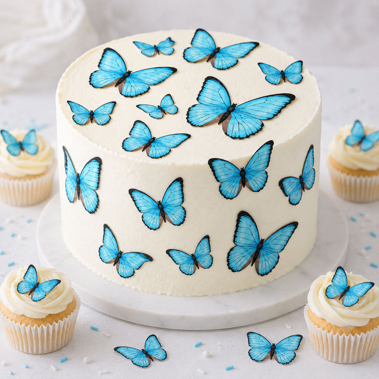 Blue butterfly cake toppers on a white cake and cupcakes, edible butterflies in multiple sizes