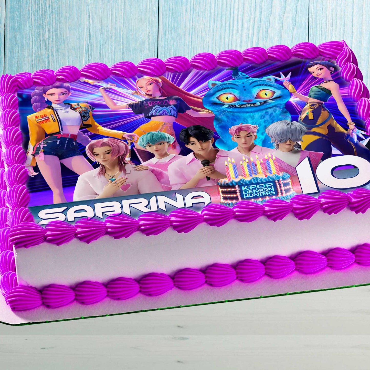 Anime-style K-Pop characters edible cake topper on a pink decorated kids birthday cake
