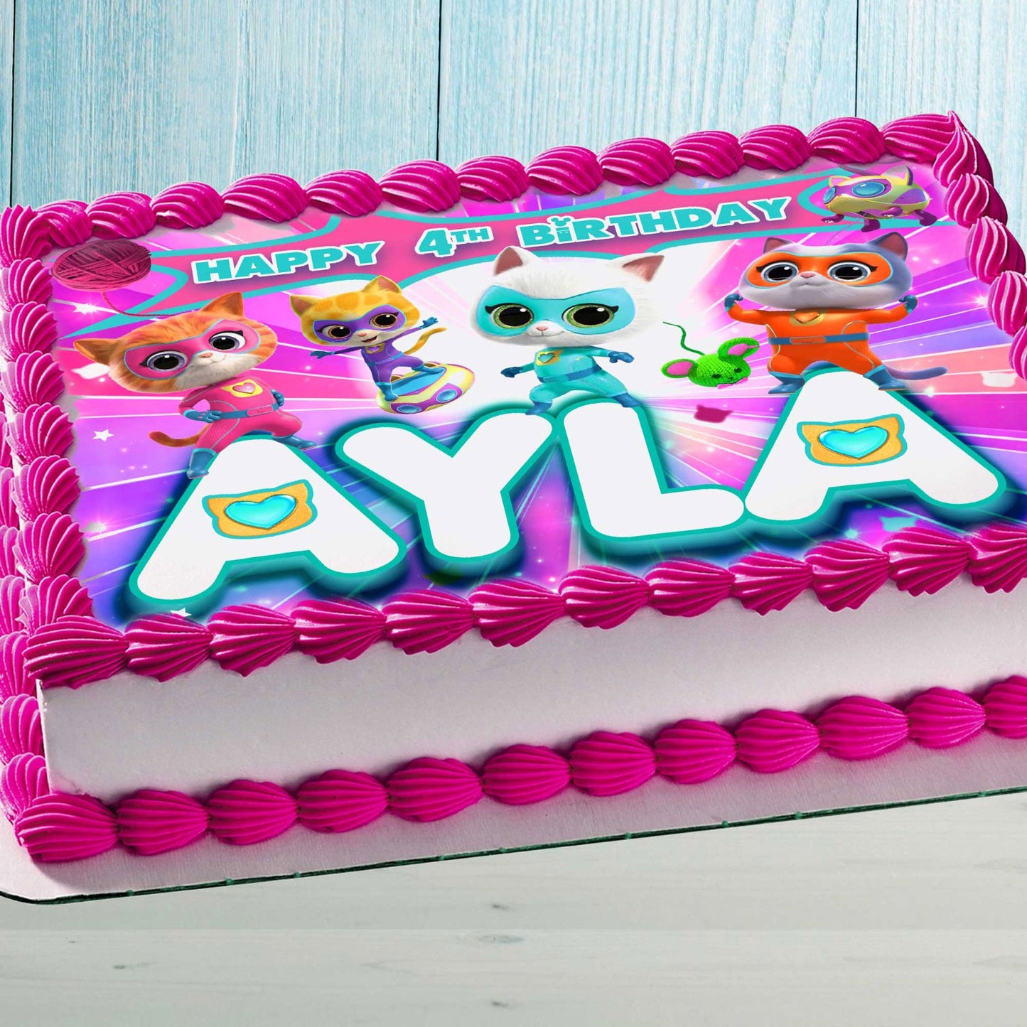 Personalized Kitty Superhero edible cake topper with custom name and age on a sheet cake with pink frosting.