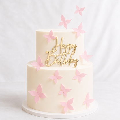 Two-tier cream cake decorated with pink wafer paper butterflies and a gold mirror acrylic Happy Birthday topper