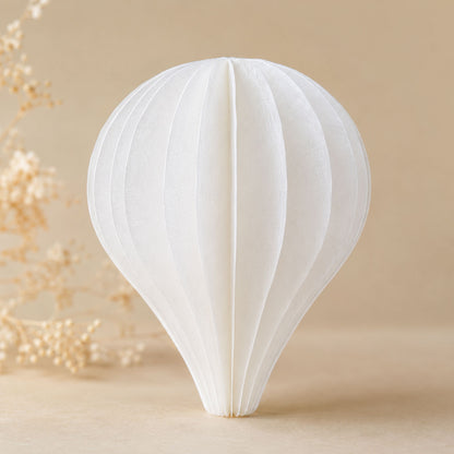 Single dimensional balloon-shaped decoration assembled from layered white wafer paper segments on a beige background