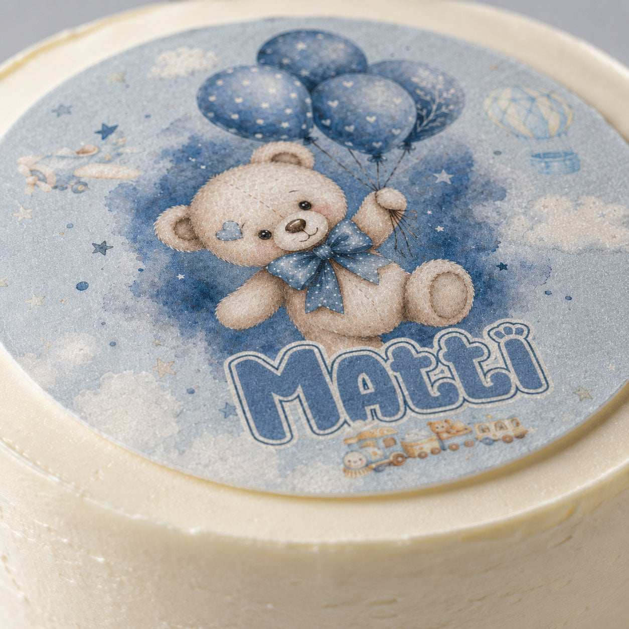 Close-up of baby boy teddy bear edible cake topper showing balloon and star detail