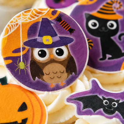 Close-up of Halloween edible toppers showing witch owl and black cat design detail on cupcakes