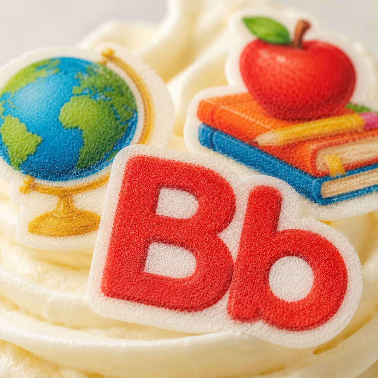 Close-up of back to school edible cupcake toppers showing globe, apple and books detail