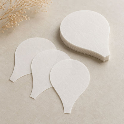 Stack and three loose flat white wafer paper balloon-shaped segments on a beige tabletop