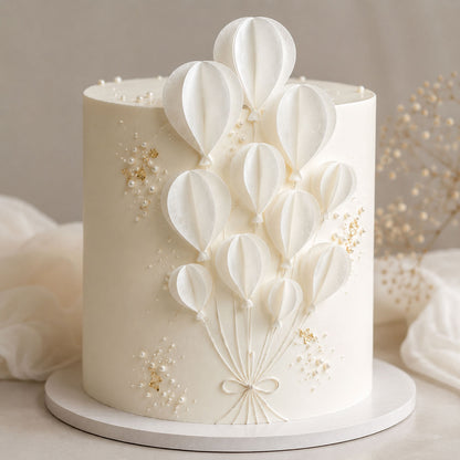 Ivory cake with pearl and gold-leaf accents decorated with a bouquet of assembled white wafer paper balloon segments